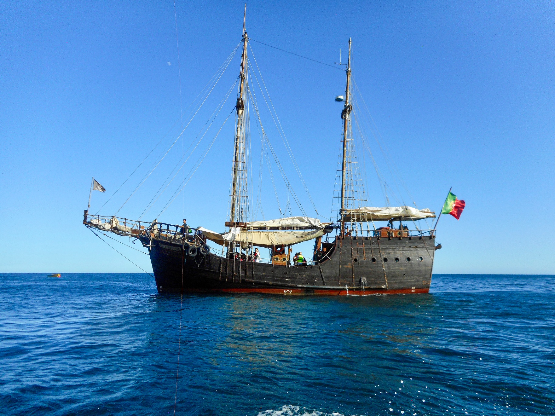 Wooden tall ship with Portuguese flag anchored on calm blue Atlantic water