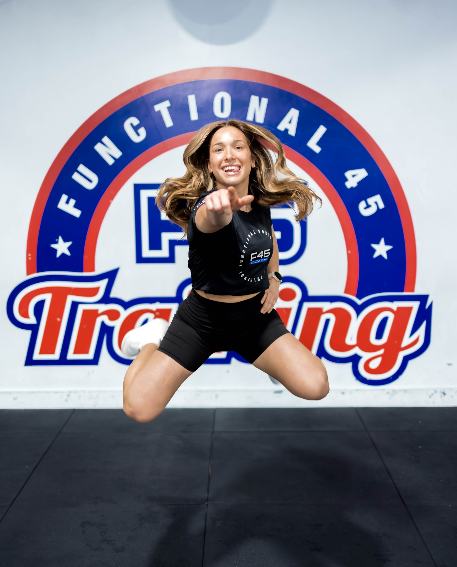 Lexi mid-jump in front of an F45 Training logo