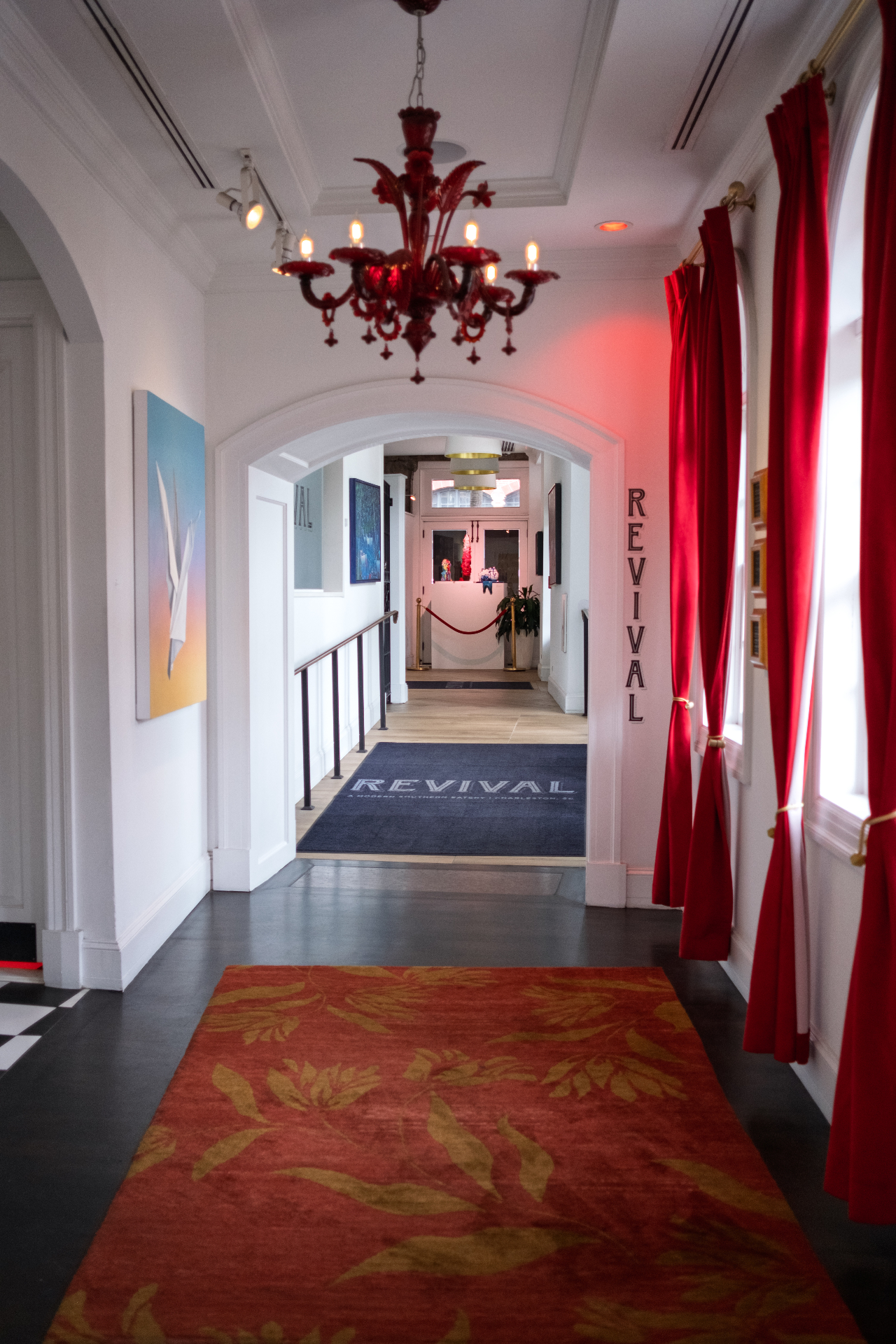 Red Murano chandelier and crimson curtains framing the entry to Revival, a Charleston southern eatery