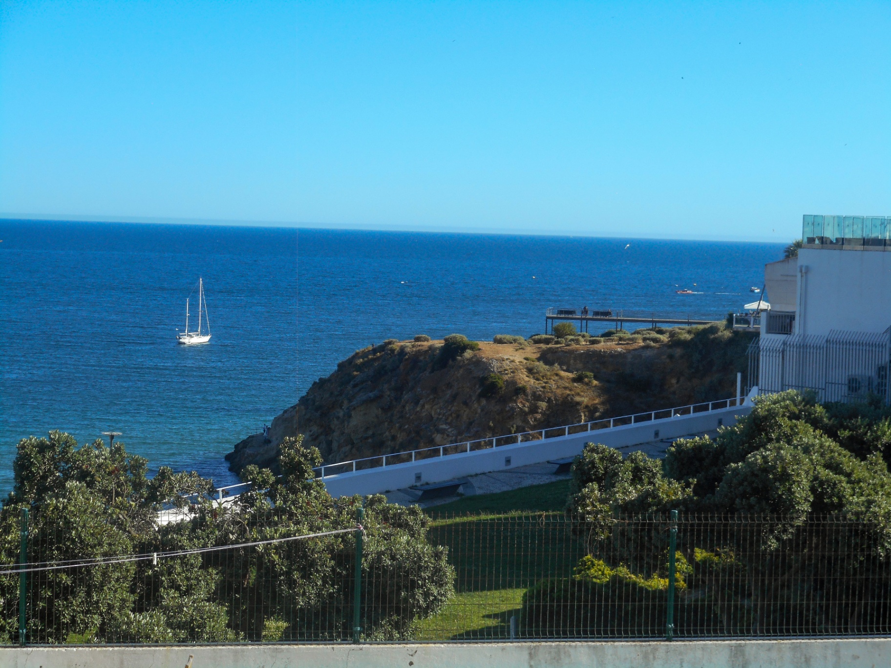 Lone sailboat anchored off a cliffside cove on the Algarve coast