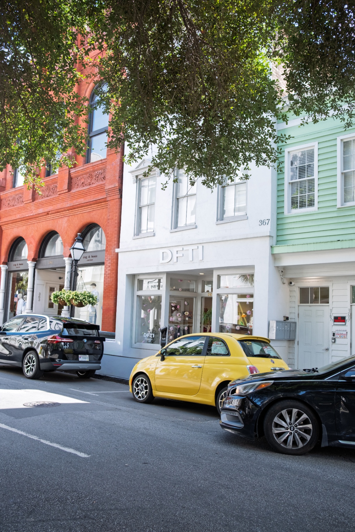 Colorful Charleston storefronts on King Street with a yellow Fiat